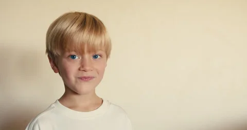 A close-up of a handsome fair-haired caucasian boy, 6 years old, looking into Video stock 324766191