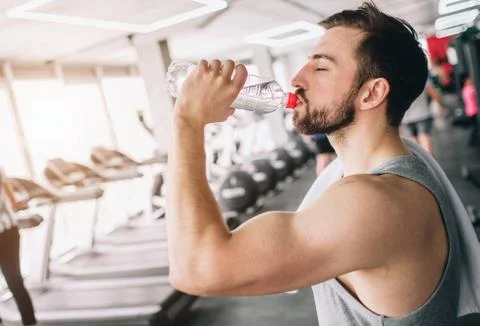 Close up of a handsome guy drinking water from the bottle and looking straight Stockfoto's