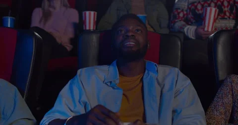 Close up of handsome guy watching action film in cinema. Young african man Stock Footage
