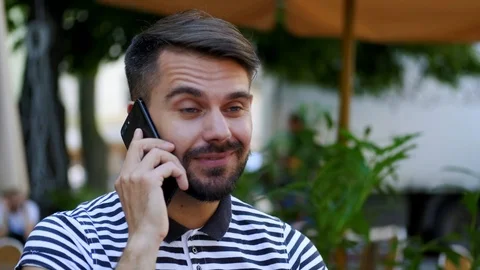 Close up of handsome happy bearded man dressed in striped T-shirt talking by sma Stock Footage 112353792