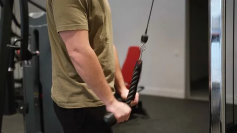 Close-up of a handsome man doing exercises with weights for triceps in the gym Stock Footage 239669739