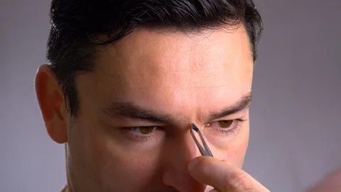 Close up handsome man in front of a mirror cares for his face. pulls out excess Stock-Footage 101792982