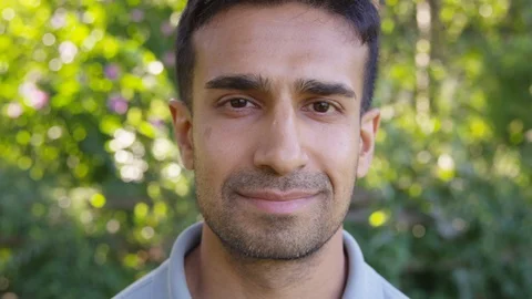 Close Up - Handsome man looks into the camera and lights up with a smile - Slow Stock Footage 125160088