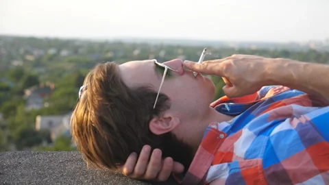 Close up of handsome man in sunglasses lying on roof and smoking cigarette Stock-Footage 104049618
