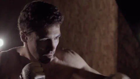 Close-up of handsome strong boxer working out using boxing bag. 库存影片 76916505