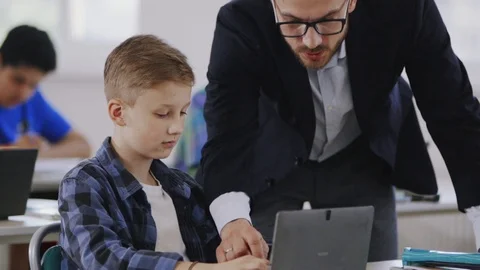 Close-up of handsome teacher helping the pupil study computer science during an Stock Footage 111969924