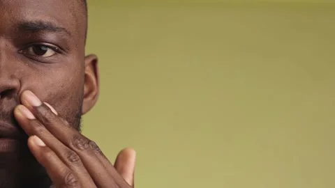 Close-up of handsome young black man massaging face cream looking at camera 스톡 동영상 233612598