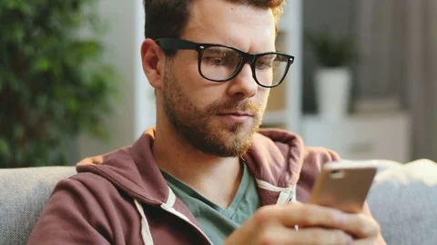 Close up of the handsome young caucasian man in glasses typing and texting on Stock Footage 83328213