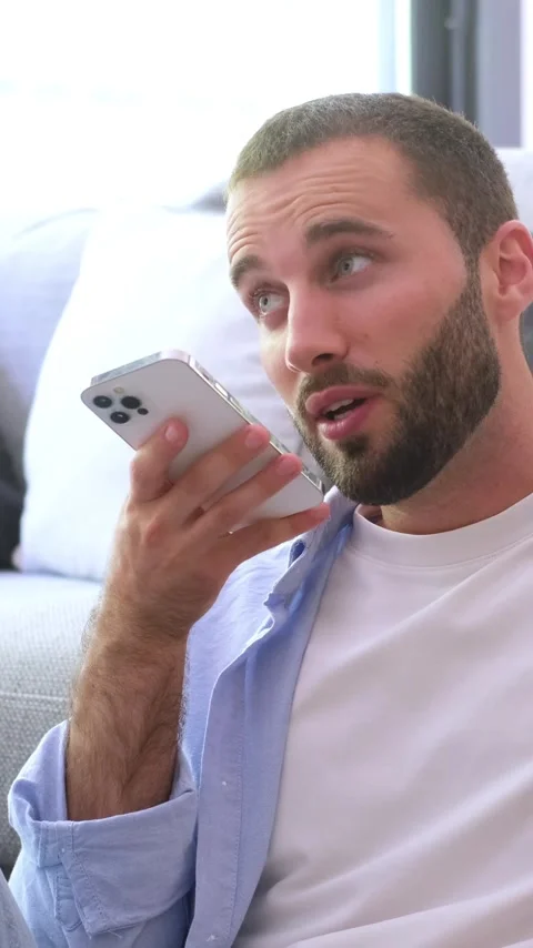Close-up of a handsome young man with a beard comfortably sitting on a sofa Vídeos de archivo 344780742