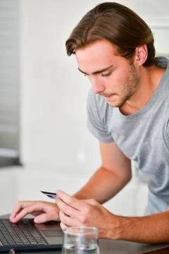 Close up of a handsome young man in the process of making an online payment u Stock Photos