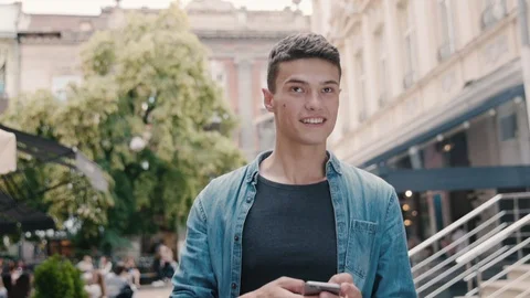 Close up Handsome Young Man Walking in the City Centre. Using his Smartphone Stock Footage 91829499