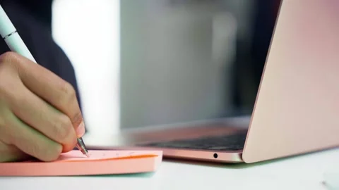 Close-Up of a Handwriting with Pen on a Sticky Note While Working on a Lapto Video stock 287561514