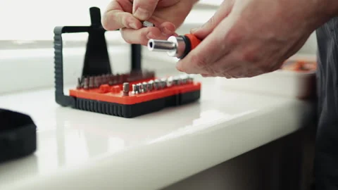 Close-up of a handyman in a jumpsuit assembling a multi-bit screwdriver, profess Vídeo Stock 335643469