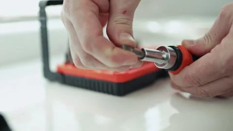Close-up of a handyman in a jumpsuit assembling a multi-bit screwdriver, profess Видео 335643952