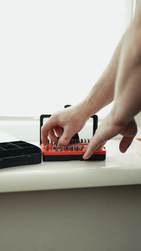 Close-up of a handyman in a jumpsuit assembling a multi-bit screwdriver, profess Stock-Footage 335644134