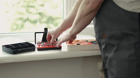 Close-up of a handyman in a jumpsuit assembling a multi-bit screwdriver, profess Vídeo Stock 335644345