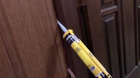 Close up of handyman using yellow caulking gun to apply sealant Video stock 346159580