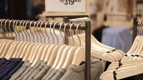 Close-up of hangers with clothes in a store, clothes for sale hang on wooden Stock Footage 188670291