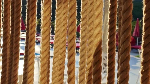 Close up of hanging ropes providing glimpse of resort pool area Vidéo 312122615