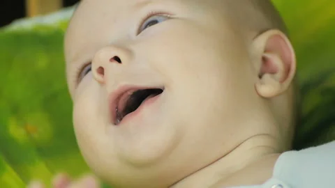 Close-up of a happy baby looking at the camera and smiling in slow motion. Video stock 98536375