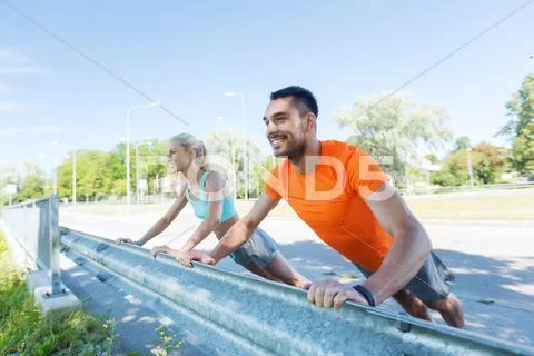 Close up of happy couple doing push-ups outdoors Stock Photos
