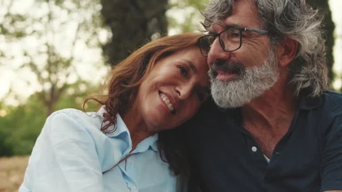 Close up, happy elderly couple sitting in the park holding hands and smiling Stock Footage 253711076