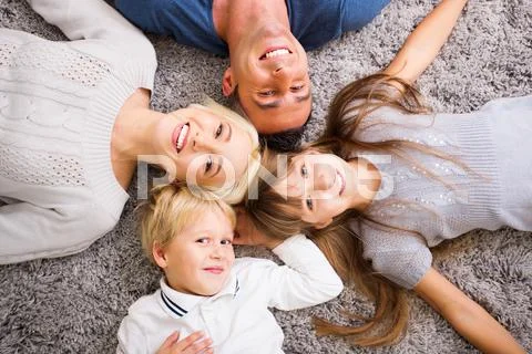 Close-up of happy family lying on carpet and looking up Stock Photos