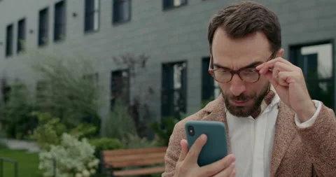 Close up of happy man in glasses checking smartphone content and celebrating Video stock 144764704