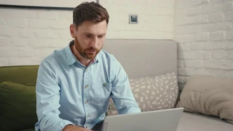 Close up happy man reading good news on laptop computer sitting on sofa at home Stock Footage 132539899