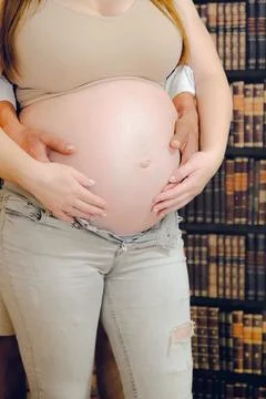 Close-up of a happy married couple's hands lying on their stomachs, expecti.. Stock Photos