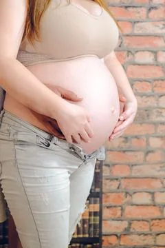 Close-up of a happy married couple's hands lying on their stomachs, expecti.. Stock Photos