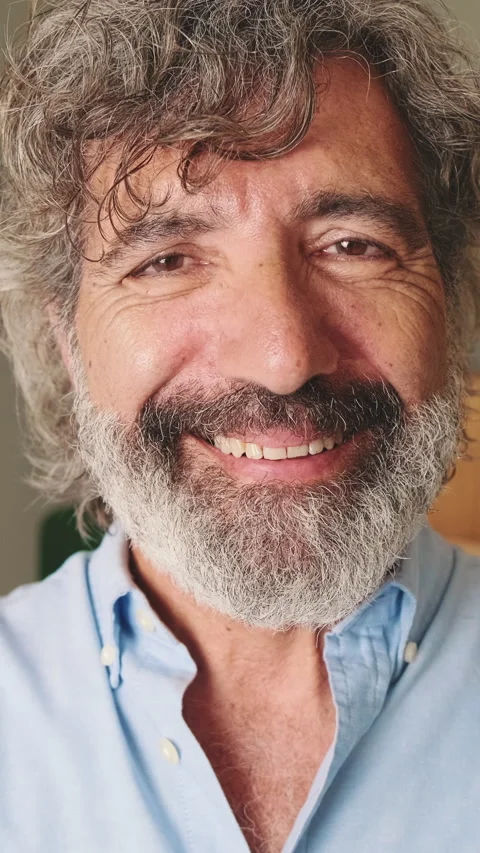 Close-up of happy middle-aged man, with gray hair, standing in the living room Stockbeeldmateriaal 252502395