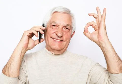Close up of happy old man using smartphone and show ok desture over white Stock Photos