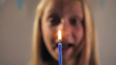Close-up Happy smiling girl blows out a candle on a birthday cake. focus on the Stock Footage 202201675