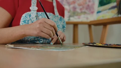 Close up of happy smiling painter sitting in her studio and painting on a list Stock Footage 74198937