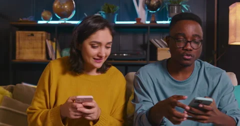Close-up happy young multiethnic couple use mobile phones surfing internet Stock Footage 172116482