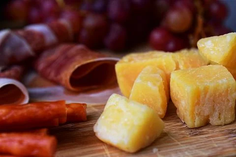 Close-up of hard cheese cubes, shallow depth of field. Parmesan on wooden boa Stock Photos