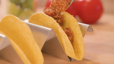 Close-up of hard corn taco shells, partially filled with seasoned meat and a Stock Footage 309001909