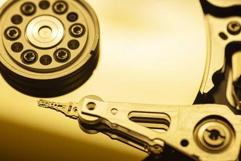  Close-up of a hard disk drive s read/write head accessing data on a golde... Stock Photos