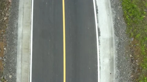 Close up of a hardened black colored road with a yellow line in the middle Stock Footage 165845700