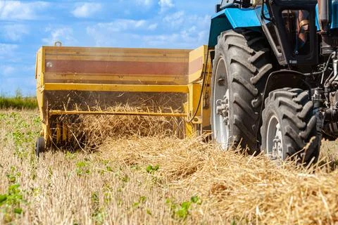 Close-up of hay baling with a tractor using a baler on a cloudy summer day, a Stock Photos