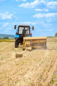Close-up of hay baling with a tractor using a baler on a cloudy summer day, a Stock Photos