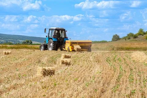 Close-up of hay baling with a tractor using a baler on a cloudy summer day, a Stock Photos