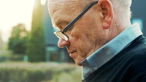 Close up of head belonging to senior man who is looking down while using phone Stock Footage 104608331