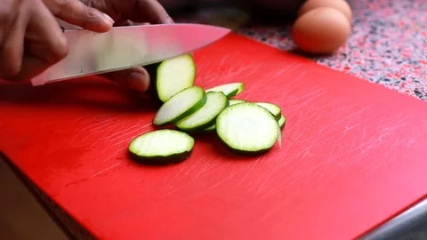 Close up of head chef chopping courgette on a red cutting board in kitchen Stock Footage 126700116