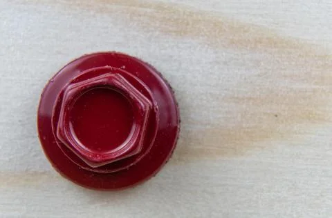 Close-up of the head of a red roofing self-tapping screw in a wooden board. Stock Photos