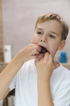 Close up head shot mirror reflection of a happy boy flossing his teeth. Stock Photos