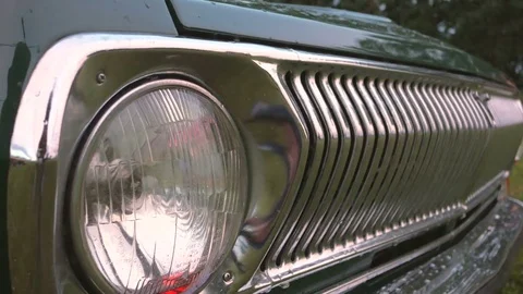 Close up of headlight and front grille of old car in the rain. 4K UHD video. Video stock 77624703