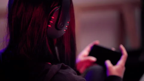 Close-up headphone playing games on cellphone. Asian woman sitting on sofa. Stock Footage 175649767