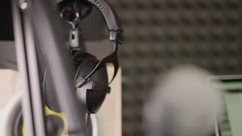 Close-Up of Headphones Hanging on Mic Stand in Blurred Recording Studio Stock Footage 283136097